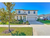 Two-story house with attached garage, landscaping, and a tree in front at 7121 Estero Ct, Apollo Beach, FL 33572