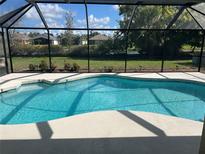 A screened-in pool offers a private oasis with clear blue water and a view of the lush greenery beyond at 1336 Roosevelt Dr, Venice, FL 34293