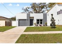 Modern home featuring a gray brick facade, gray garage door, tidy lawn and walkway at 3508 E 11Th Ave, Tampa, FL 33605
