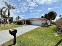 Charming single-story home with a well-manicured lawn, palm trees, and a two-car garage at 468 Ceil Dr, Nokomis, FL 34275