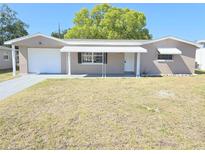 Charming single-story home featuring a front porch, attached garage, and well-maintained lawn at 4823 Blossom Dr, Holiday, FL 34690