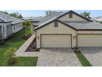 Beautiful paired villa featuring a two-car garage, landscaped grounds, and a brick paver driveway at 17986 Cherished Loop, Bradenton, FL 34211