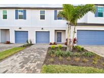 Charming townhome with blue garage doors, shutters, brick driveway and beautifully landscaped front yard at 5425 Tripoli Dr, Palmetto, FL 34221
