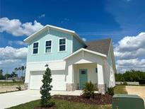 Beautiful two-story home with a light blue exterior, a two-car garage, and a well-manicured lawn at 7959 Chandler Lake Ct, Hudson, FL 34667