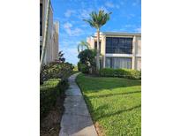 A beautiful condo exterior featuring lush landscaping and well-maintained grounds, with a sidewalk in view at 8744 54Th W Ave # 8744, Bradenton, FL 34210