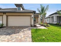 A lovely home featuring an attached two-car garage with a brick-paved driveway and a manicured lawn at 18032 Cherished Loop, Bradenton, FL 34211