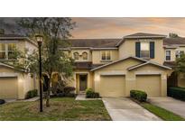 Exterior shot of yellow townhomes with well-maintained lawns at 10821 Great Carlisle Ct, Riverview, FL 33578
