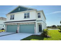 Two-story home featuring a two-car garage, decorative stone accents, and well-maintained front lawn with a view of the lake at 13797 Emerald Fields Dr # 138, Hudson, FL 34667
