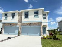Charming two-story home featuring stone accents, a blue garage door, and inviting landscaping at 14004 Emerald Fields Dr, Hudson, FL 34667