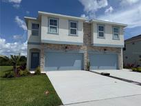 Beautiful two-story townhome with stone accents, light blue trim, and a two-car garage at 14012 Emerald Fields Dr, Hudson, FL 34667