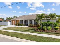 Charming single-story home featuring arched windows, a manicured lawn, and lush landscaping at 567 Whippoorwill Dr, Venice, FL 34293