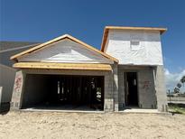 New home construction showcasing the garage and main entry under a clear blue sky at 7979 Chandler Lake Ct, Hudson, FL 34667