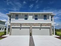 Charming townhome featuring a stone facade, two-car garage, and a well-manicured lawn at 13904 Emerald Fields Dr, Hudson, FL 34667