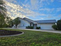 House exterior featuring a metal roof and landscaping at 975 Coronado Dr, Punta Gorda, FL 33950