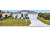 Charming single-story home featuring a neutral color scheme, two-car garage, and a well-manicured lawn at 13527 Ainsworth Ln, Port Charlotte, FL 33981