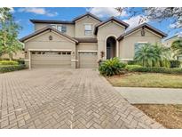 Two-story house with tan exterior, three-car garage, and landscaping at 1005 Sonesta Ave, Brandon, FL 33511
