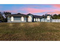 One-story home with light blue exterior, landscaping, and a fenced backyard at 18482 Holly Ave, Port Charlotte, FL 33948