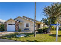 Cute yellow house with brick accents, attached garage, and a small front yard at 5846 Greenbriar Ct, Zephyrhills, FL 33542