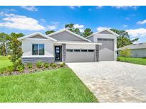 Beautiful, modern home with manicured lawn and paver driveway on a sunny day at 9093 Players Dr, Weeki Wachee, FL 34613