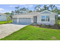 Charming single-Gathering home features a three-car garage, stone accents, and well-manicured lawn at 9109 Players Dr, Weeki Wachee, FL 34613
