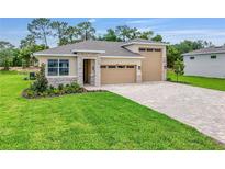 Beautiful single-Gathering home with a three-car garage, stone accents, and a well-manicured lawn at 9157 Players Dr, Weeki Wachee, FL 34613