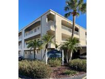 Condo building exterior featuring lush landscaping, mature palm trees and a stucco facade at 215 Valencia Blvd # 212, Belleair Bluffs, FL 33770