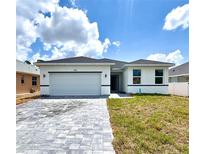 Charming single-story home with a two-car garage, light exterior, and a beautifully paved driveway at 104 Australian Dr, Rotonda West, FL 33947