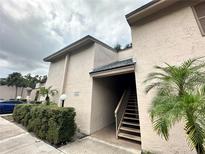Condo exterior showcasing well maintained stucco walls, green shrubbery and stairs leading to the entrance at 7522 Needle Leaf Pl # 27, Tampa, FL 33617