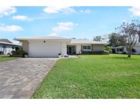 Charming single-story home featuring a brick driveway, lush lawn, and well-maintained landscaping at 1602 W Dorchester Dr, Palm Harbor, FL 34684