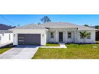 A lovely single-story home boasts a neat lawn and attractive modern garage door at 159 Antilla Dr, Rotonda West, FL 33947