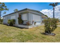 Charming single-story home featuring awnings, mature landscaping, and a well-maintained lawn under a sunny blue sky at 5619 Bayshore Rd # 312, Palmetto, FL 34221