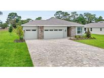Beautiful single-story home featuring stone accents, a three-car garage, and a brick-paved driveway at 9143 Players Dr, Weeki Wachee, FL 34613