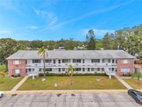 Two-story apartment complex featuring brick accents, palm trees, and exterior staircases under a bright blue sky at 2353 Shelley St # 10, Clearwater, FL 33765