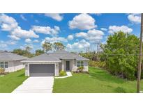 Charming single-Gathering home features a gray exterior, lush green lawn, and a two-car garage at 488 Sunset N Rd, Rotonda West, FL 33947