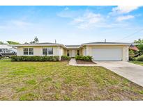 Charming single-story home featuring a two-car garage and manicured front lawn under a bright, sunny sky at 14010 102Nd Ave, Largo, FL 33774