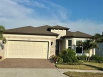 Charming single-Gathering home with a two-car garage, brick driveway, stone accents, and manicured landscaping at 5820 Shorebird Br, Land O Lakes, FL 34638