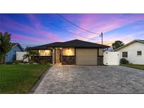 Charming single-story home featuring stone accents, a paved driveway, manicured lawn, and picturesque twilight skies at 5036 Bonito Dr, New Port Richey, FL 34652