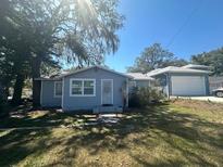 Charming single-story home with blue siding and a detached garage, surrounded by mature trees in a residential neighborhood at 8702 El Portal Dr, Tampa, FL 33604