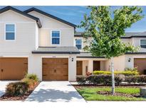 Charming two-story townhome featuring a well-manicured lawn and a welcoming front entrance and brown garage door at 5424 Companion Ln, Tampa, FL 33619