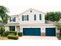 Charming two-story home featuring light gray siding, dark blue shutters, well-maintained landscaping, and a three car garage at 12236 Fairlawn Dr, Riverview, FL 33579