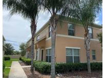 Inviting two-story townhouse with lush landscaping, mature palms, and a welcoming walkway at 9871 Trumpet Vine Loop, Trinity, FL 34655