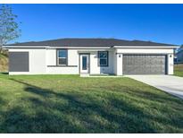 Beautiful single-story home with a well-manicured lawn and modern gray and white color scheme at 17381 Tyler Ave, Port Charlotte, FL 33948