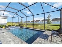 Relaxing screened-in pool area with a beautiful view of the green lawn and pond at 11330 Burgundy Dr, Venice, FL 34293