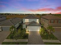 Charming two-story home with landscaped yard and paver driveway set against a colorful sunset backdrop at 6288 Winding Pine Dr, Nokomis, FL 34275