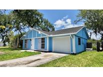 Charming home with bright blue siding, white trim, attached garage, and a well-manicured lawn at 4546 Ontario Dr, New Port Richey, FL 34652