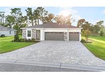 Beautiful single-story home with a gray brick driveway, stone accents, manicured lawn, and a two-car garage at 9127 Players Dr, Weeki Wachee, FL 34613