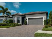 Beautiful single-story home with a paver driveway, a two-car garage, and lush landscaping at 14553 Eagle Branch Dr, Nokomis, FL 34275