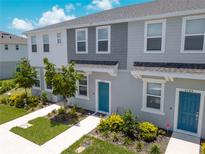 Charming townhome featuring a blue front door, manicured landscaping, and modern gray and white facade at 8540 Daybreak St, Sarasota, FL 34241