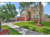 Charming home featuring a well-manicured lawn, lush landscaping, and a two-car garage at 6932 Gray Catbird Loop, Wesley Chapel, FL 33545