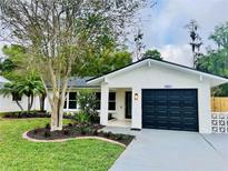 Charming home featuring a well-manicured lawn and complemented by a freshly painted exterior with lush landscaping at 801 Leeward Way, Palm Harbor, FL 34685